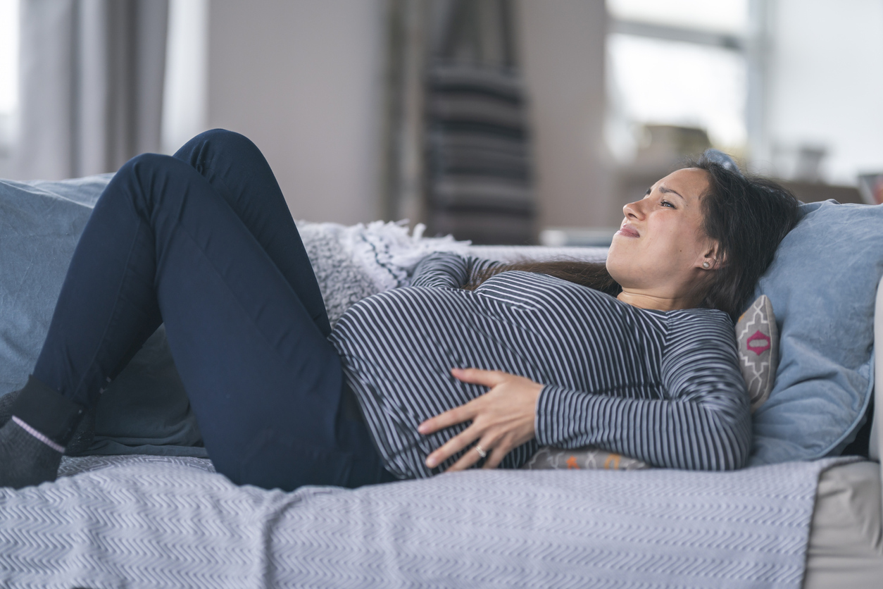 Pregnant woman laying on back on couch