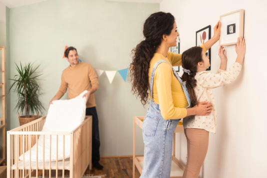Child helping mother hang artwork in room