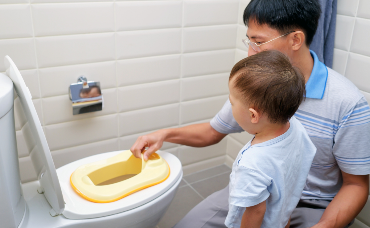 Boy and dad looking at toilet seat insert for potty training