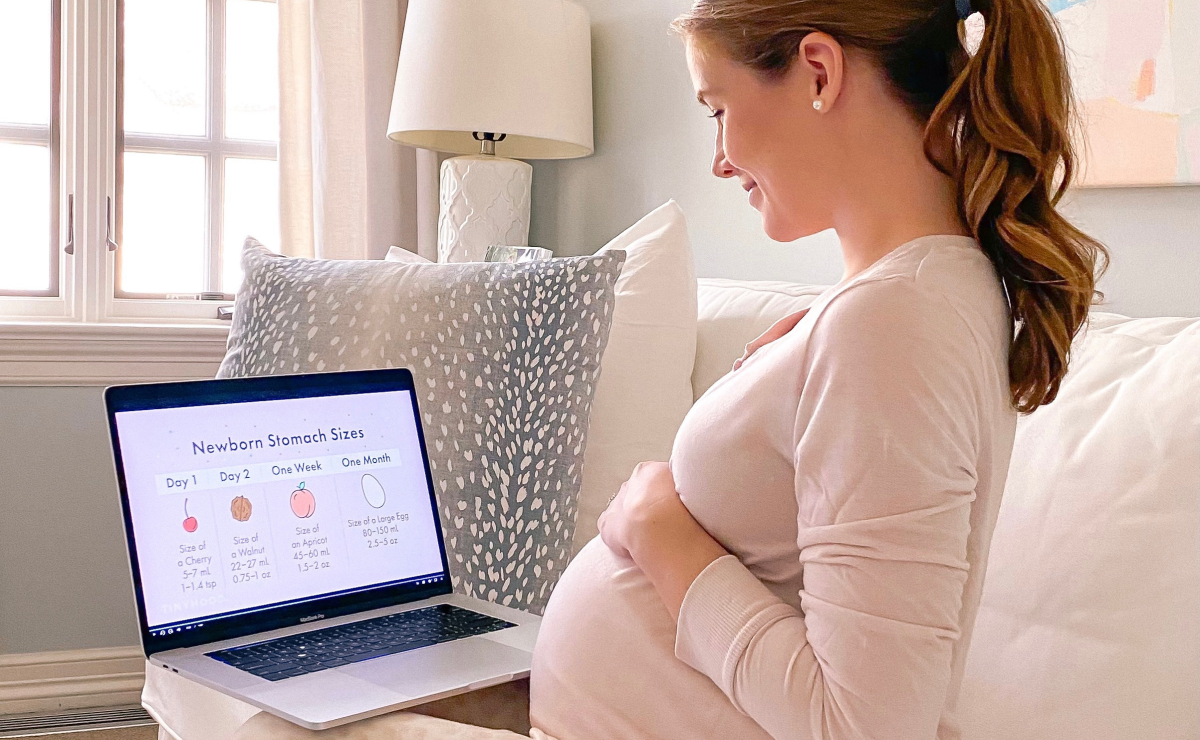 woman watching class on computer holding pregnant stomach