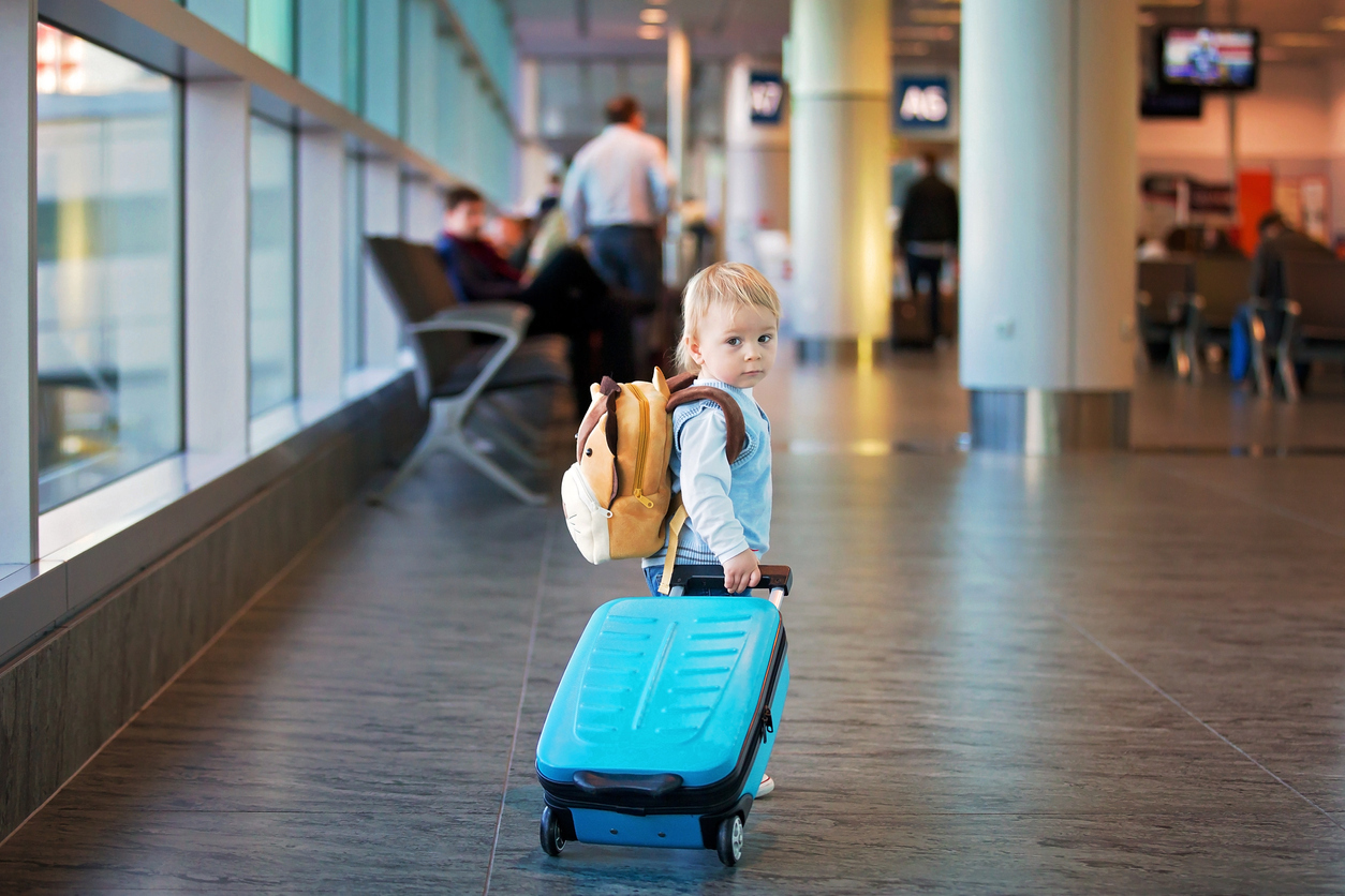 Toddler in airport holding suitcase