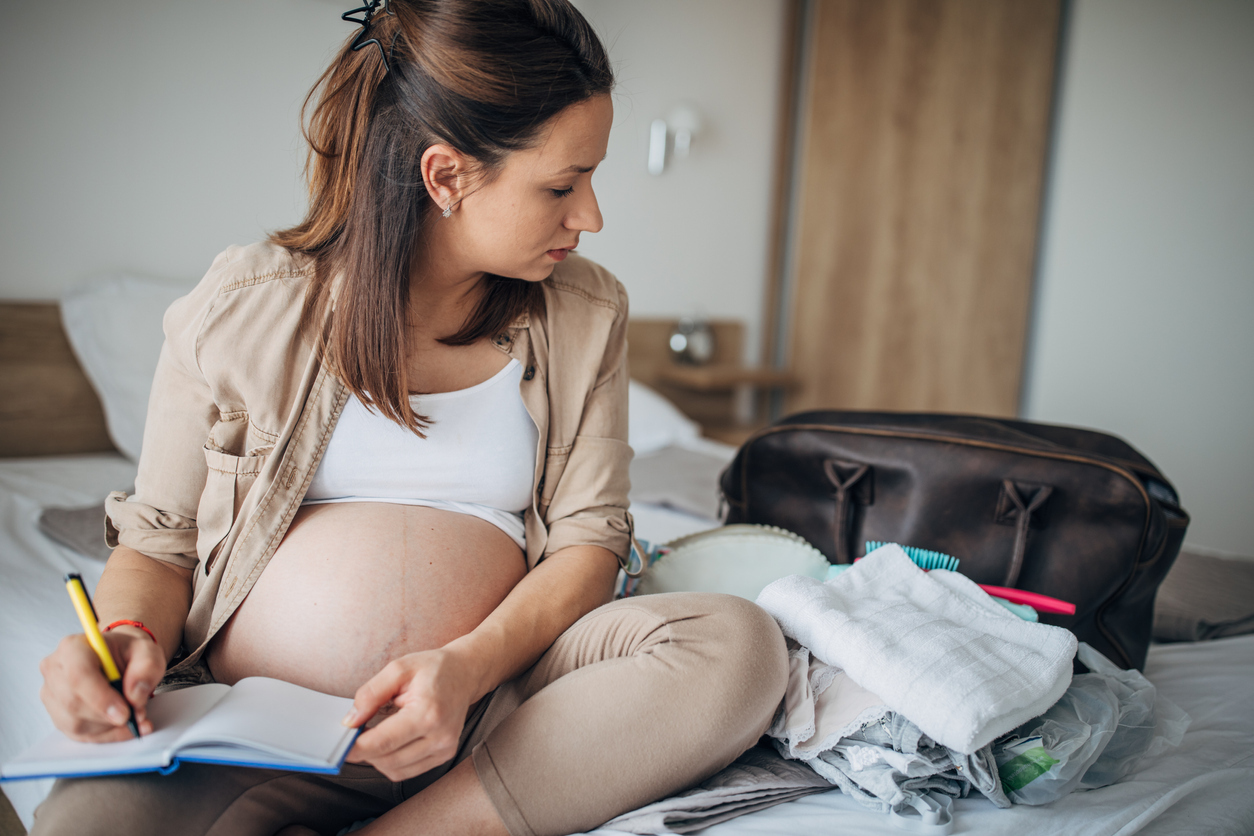 Pregnant woman packing her hospital bag on the floor of her nursery 