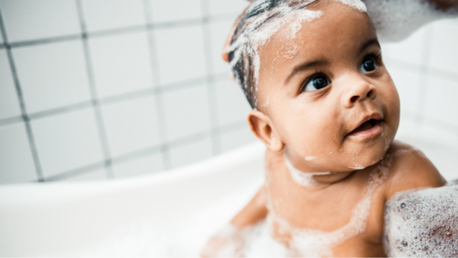 Black baby sitting in bubble bath