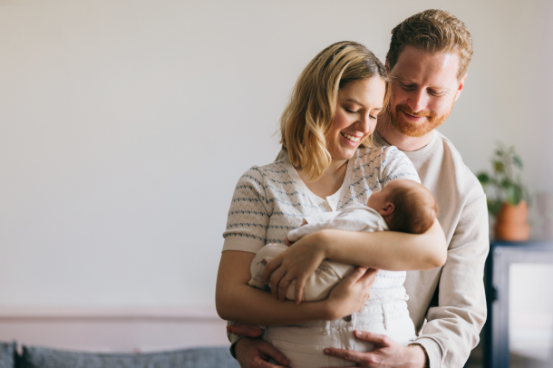 Mother holding baby, with father looking on lovingly